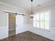 Dining room area with barn door leading to laundry area, plantation shutters, and an elegant pendant light at 63 Whistling Duck Way, Wendell, NC 27591