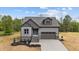 Charming new construction home featuring stone accents, a two-car garage, and a welcoming teal front door at 65 Leisure Ln # 6, Louisburg, NC 27549
