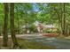 Secluded home exterior featuring lush landscaping, a circular driveway, and a mix of stone and shingle siding at 6600 Maynard Farm Rd, Chapel Hill, NC 27516