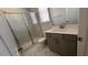 Modern bathroom features a glass-enclosed shower with marble tile, vanity, white countertop, and window at 705 Blue Pointe Path, Apex, NC 27523