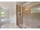 Tiled shower with glass door and modern fixtures in a well-lit bathroom with a window at 7104 Rex Rd, Holly Springs, NC 27540