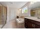 Bathroom with a large soaking tub, double sinks with dark wood cabinets, and a glass shower at 7104 Rex Rd, Holly Springs, NC 27540