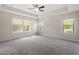Large bedroom with plush carpeting, tray ceiling, fan, and lots of natural light at 7104 Rex Rd, Holly Springs, NC 27540