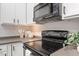 Modern kitchen with black stove and microwave, white cabinets and dark granite countertops at 7838 Spungold St, Raleigh, NC 27617