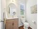 Powder room with oval mirror, shaker cabinets, and natural light at 100 Winterberry Ln, Holly Springs, NC 27540