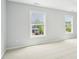 Bedroom featuring carpeted floors, light gray walls and two bright windows at 100 Winterberry Ln, Holly Springs, NC 27540