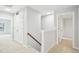 Hallway featuring carpeted floor, doors, staircase with wooden railing and light gray walls at 100 Winterberry Ln, Holly Springs, NC 27540