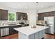 Modern kitchen features dark cabinets, stainless appliances, and a large center island at 100 Winterberry Ln, Holly Springs, NC 27540