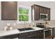 Close up of kitchen featuring stainless appliances, black sink, and gray backsplash at 100 Winterberry Ln, Holly Springs, NC 27540