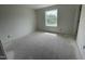 A bright, neutral bedroom with concrete floors and a large window overlooking the outdoors at 1031 Mountain Crown St, Durham, NC 27703