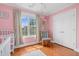 A bright and airy pink-themed room with a crib, rocking chair, and a view of the backyard at 11 Glen Valley Ct, Angier, NC 27501