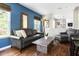Stylish living room featuring a leather sofa, modern coffee table, and accent mirror on a blue accent wall at 111 Sir Richard Ln, Chapel Hill, NC 27517