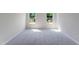 Bright bedroom with carpet, two windows, white walls, and a door at 1114 Merlot Hills Ln, Durham, NC 27704