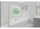 A stunning main bathroom featuring a soaking tub with marble tile surround and a large window at 11808 Venture Oak Way, Raleigh, NC 27613