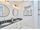 Bright bathroom featuring a double vanity with granite countertops and round framed mirrors at 1203 Queensbury Cir, Durham, NC 27713