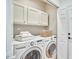 Well-lit laundry room with washer, dryer, and white cabinets for storage at 1203 Queensbury Cir, Durham, NC 27713
