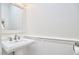 Bright powder room featuring pedestal sink, paneled wall, and decorative mirror at 1203 Queensbury Cir, Durham, NC 27713