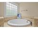 Bright bathroom featuring a large soaking tub with decorative tile surround and large window at 1209 Kingston Ridge Rd, Cary, NC 27511