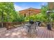 Outdoor deck features a dining table, grill, patio umbrella and view to wooded back yard at 1209 Kingston Ridge Rd, Cary, NC 27511