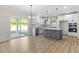 Bright, open kitchen and outdoor view features a gray island, white cabinets, stainless appliances and light wood floors at 1236 Cricket St, Elon, NC 27244
