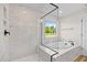 Bathroom featuring a tub, shower, and large window at 1302 Cricket St, Elon, NC 27244