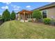 Landscaped backyard with healthy lawn, decorative trees, and a wooden pergola shading a concrete patio at 1305 Chronicle Dr, Durham, NC 27703