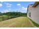 Expansive backyard features a well-maintained lawn and a black fence bordering a serene pond and lush green trees at 1305 Chronicle Dr, Durham, NC 27703
