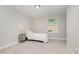 A simple bedroom featuring neutral carpeting, a twin bed, and a side table with a lamp near the window at 132 Deardom Way, Chapel Hill, NC 27516
