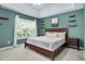 Green bedroom with a bed, bedside tables, shelves, a ceiling fan, and window views at 136 River Pearl St, Raleigh, NC 27603