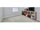 Cozy bedroom with a window and a wooden shelf, carpeted floors, and soft natural light at 136 River Pearl St, Raleigh, NC 27603