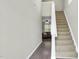 View of hallway with wood-look floors, neutral wall paint, carpeted staircase and living room beyond at 136 River Pearl St, Raleigh, NC 27603