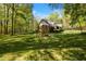 Well-manicured backyard with mature trees surrounding a brick and siding home, offering a serene and private outdoor space at 1415 Meadow Wind Ln, Hillsborough, NC 27278