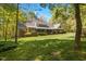 Spacious backyard featuring a well-kept lawn, mature trees, and a charming two-story home with a screened porch at 1415 Meadow Wind Ln, Hillsborough, NC 27278