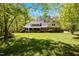 Expansive backyard with a well-maintained lawn, mature trees, and a charming two-story home with a screened-in porch at 1415 Meadow Wind Ln, Hillsborough, NC 27278