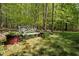 Secluded backyard featuring a wrought iron bench with potted plants and trees, creating a peaceful outdoor retreat at 1415 Meadow Wind Ln, Hillsborough, NC 27278