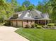 Brick home with attached garage and lush greenery offers ample parking and curb appeal at 1415 Meadow Wind Ln, Hillsborough, NC 27278