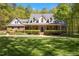 Attractive two-story brick home with dormer windows, a covered front porch, and lush landscaping in a well-manicured yard at 1415 Meadow Wind Ln, Hillsborough, NC 27278