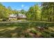 Inviting two-story home with a lush front yard, mature trees, and a cozy bench for enjoying the serene outdoor space at 1415 Meadow Wind Ln, Hillsborough, NC 27278