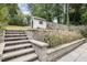 Landscaped backyard features steps leading to a grassy area with a small shed, surrounded by trees at 1422 Banbury Rd, Raleigh, NC 27607