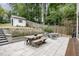 This patio features stone pavers, an outdoor dining table, fire pit, and a shed nestled on a stone ledge at 1422 Banbury Rd, Raleigh, NC 27607