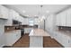Bright, spacious kitchen with white cabinets, island, stainless appliances, and designer lighting at 2328 Beeblossom Pl, Fuquay Varina, NC 27526