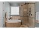 Well-lit bathroom displaying a corner tub, patterned window, and a large walk-in shower with glass door at 255 Capellan St, Wake Forest, NC 27587
