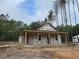 New home under construction featuring a covered porch, surrounded by tall trees and construction materials at 329 Green Pines Estates Dr, Kenly, NC 27542