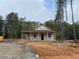 New home under construction with covered porch, surrounded by tall trees, on a partially cleared lot at 329 Green Pines Estates Dr, Kenly, NC 27542