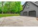 Attached two-car garage with a large concrete driveway and a spacious backyard surrounded by lush trees at 401 Brinkman Ct, Raleigh, NC 27614
