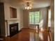 Cozy living room with a fireplace, ceiling fan, hardwood floors, and a bright window at 5033 Amber Clay Ln, Raleigh, NC 27612