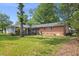 Expansive, grassy backyard featuring a brick home with a porch and mature trees at 515 Oakwood Ln, Graham, NC 27253