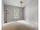 Minimalist bedroom with neutral carpet, large window with treed view, and ceiling fan at 5420 Royal Troon Dr, Raleigh, NC 27604
