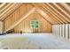 Unfinished attic space with exposed wood beams and a window, offering potential for customization and expansion at 669 Balmoral St, Clayton, NC 27520