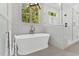 Bright bathroom featuring a standalone tub, walk-in shower with glass door, and a large window with natural light at 669 Balmoral St, Clayton, NC 27520